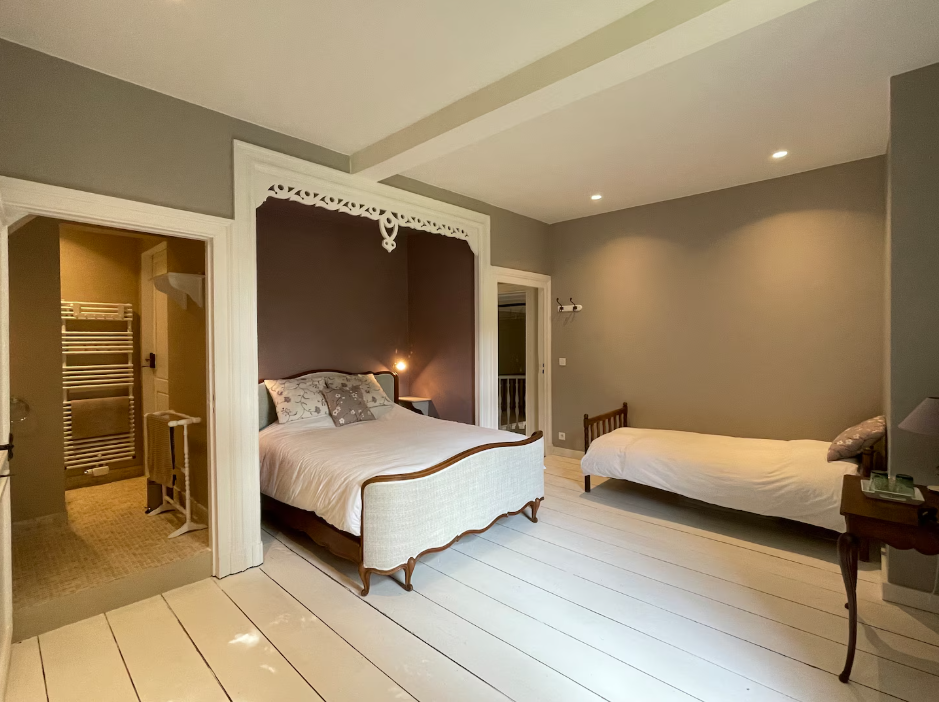 Large room with a carved alcove holding a wooden double bed and a separate single bed